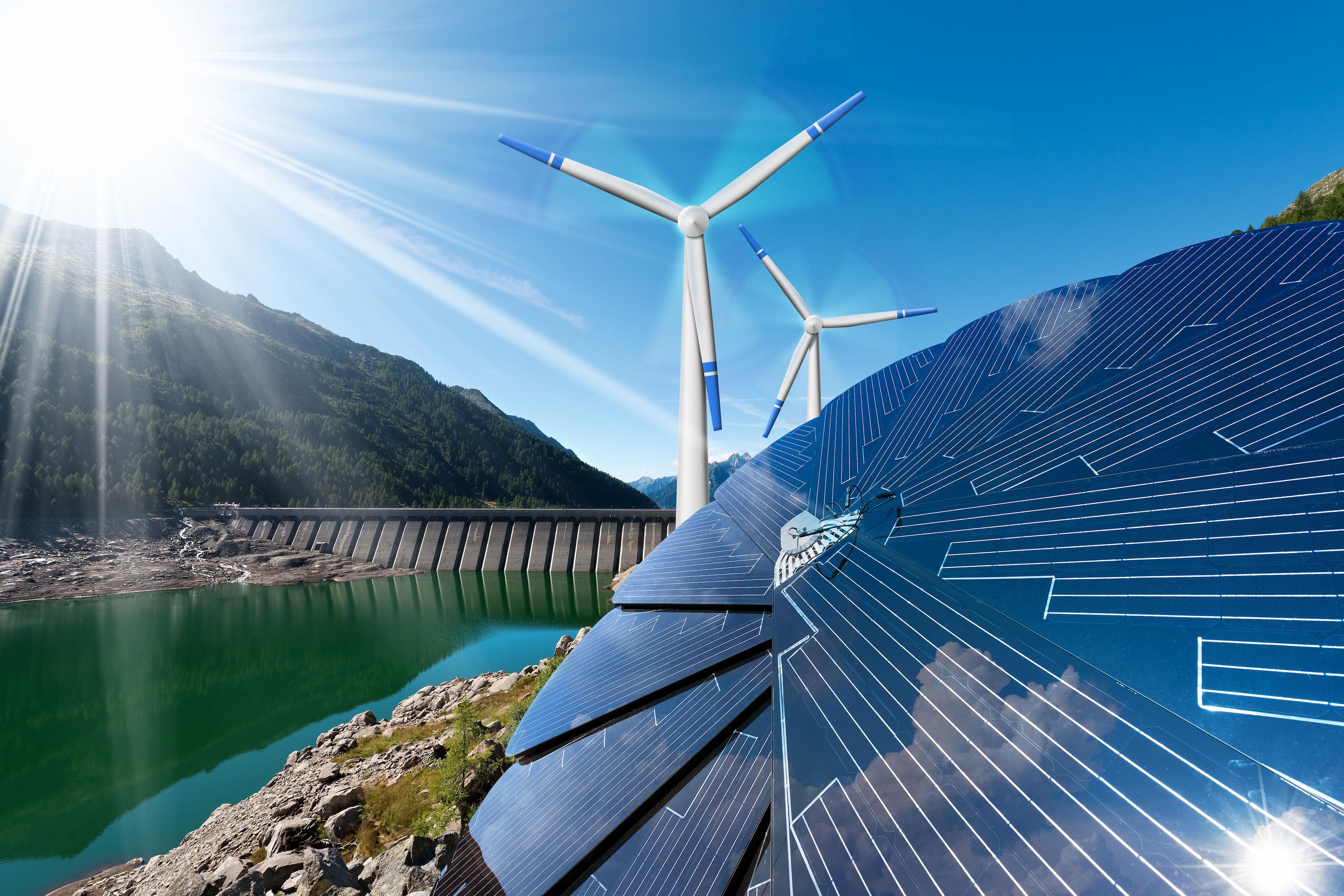 Windmills and solar panels surrounded by mountains and water by a dam